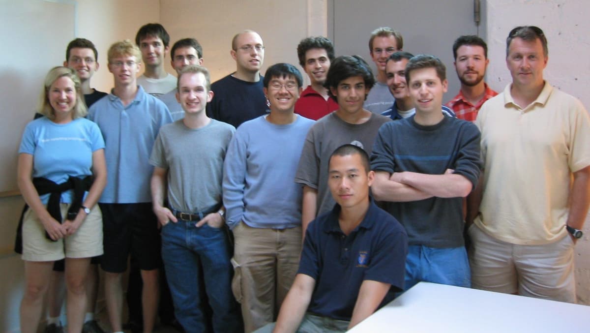 People gathered and talking in an early computer lab setting.